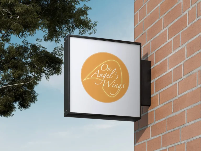 On Angel's Wings sign outside on brick wall
