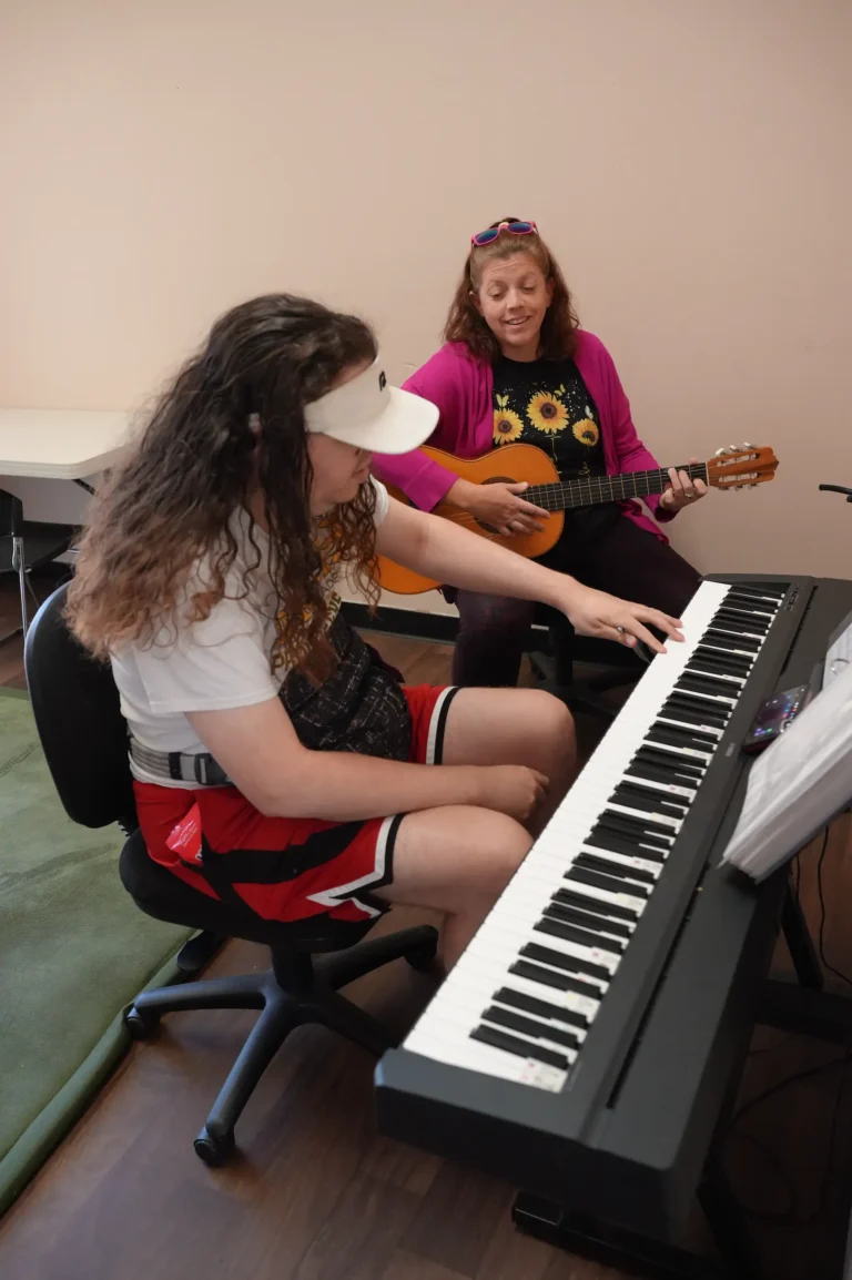 caregiver playing guitar with individual playing piano