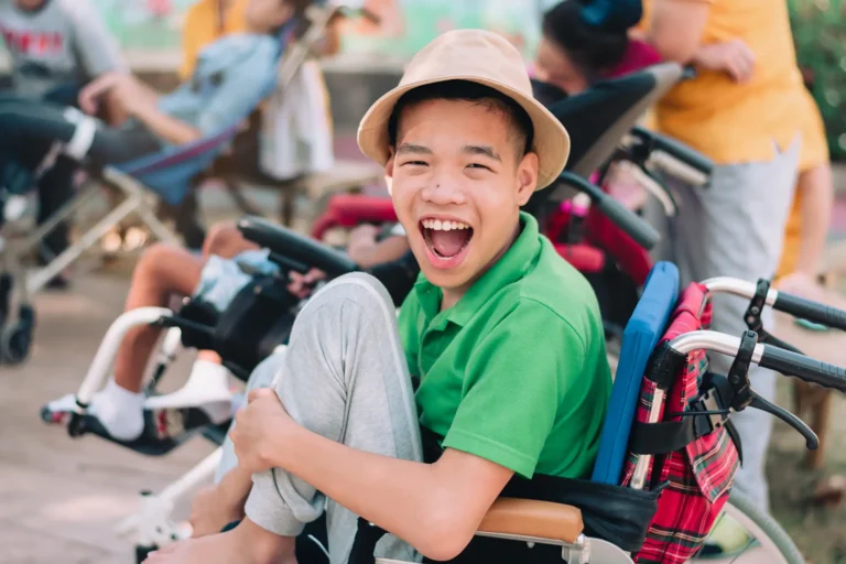 smiling young man sitting in wheelchair with other people
